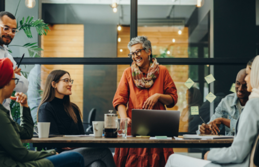 Team collaborating in a modern office with sticky notes on a glass wall, laptops, and notebooks on the table.
