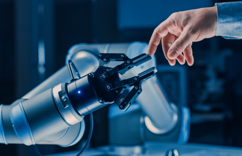 Robotic arm reaching to touch human fingertip in industrial or lab setting.