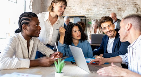 Team collaboration around table with laptops and documents in modern workspace.