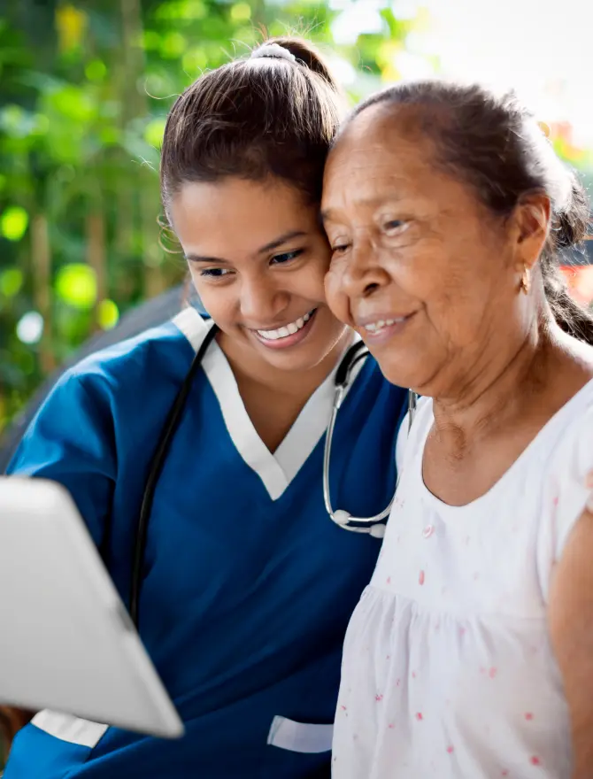Caregiver showing content on a tablet to an elderly woman