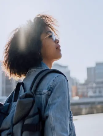 Girl in a city looking at the sun