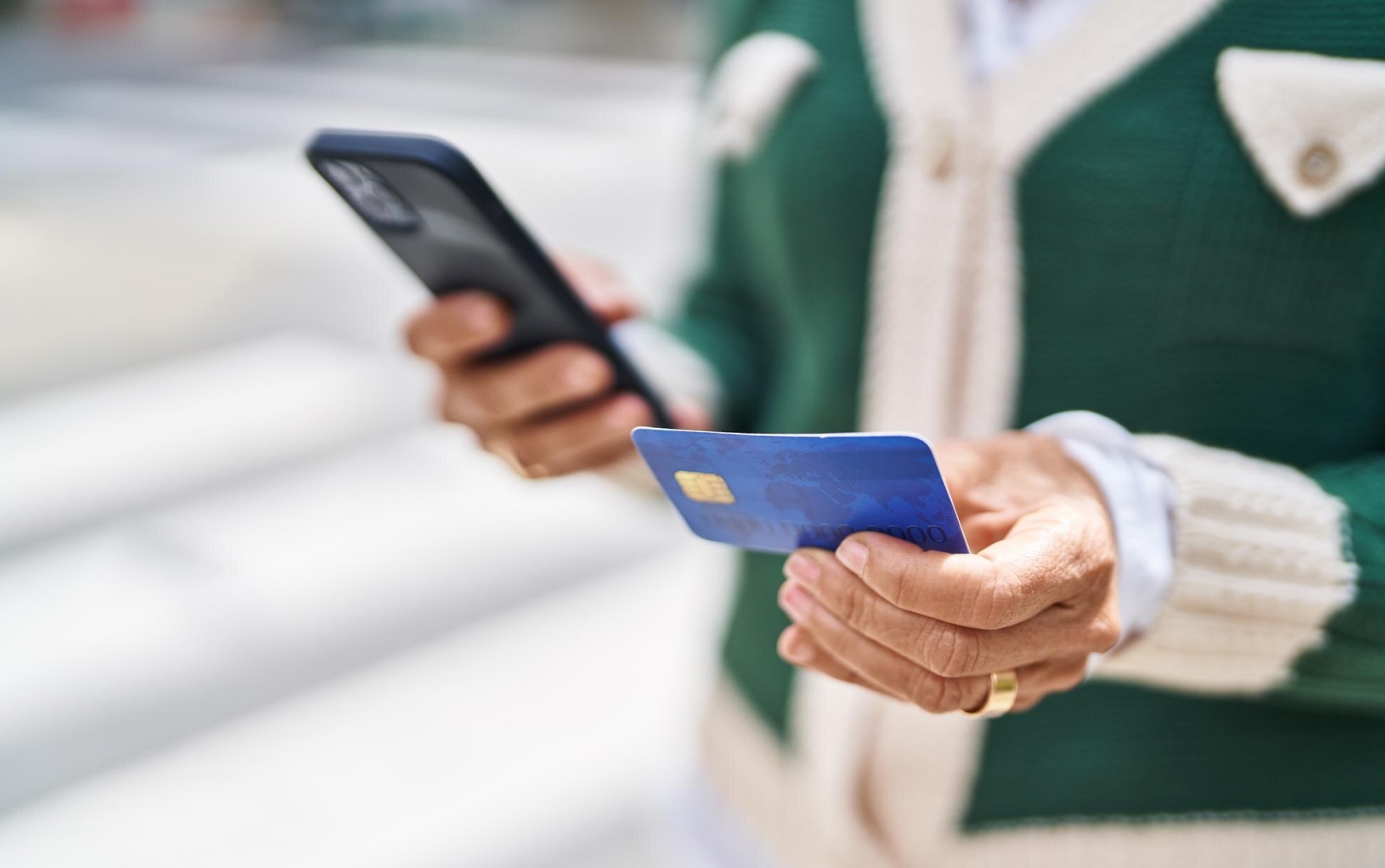 Person checking information on their mobile phone, while looking at their credit card.