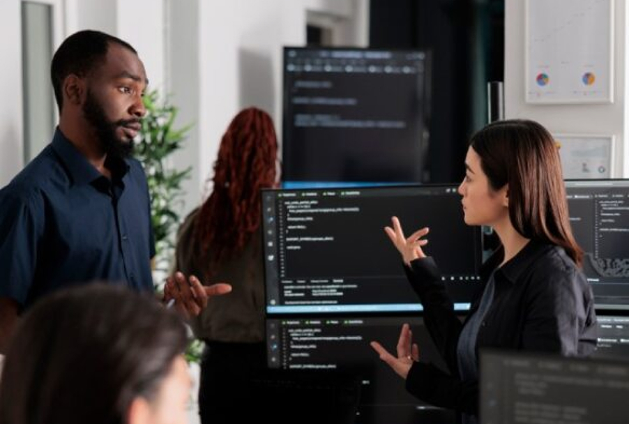 Young woman talking about coding with a black colleague